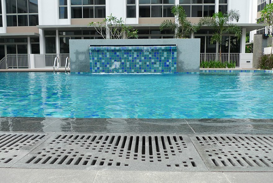 Jonite stone pool grates around a pool with a waterfall feature at Charlton Villa