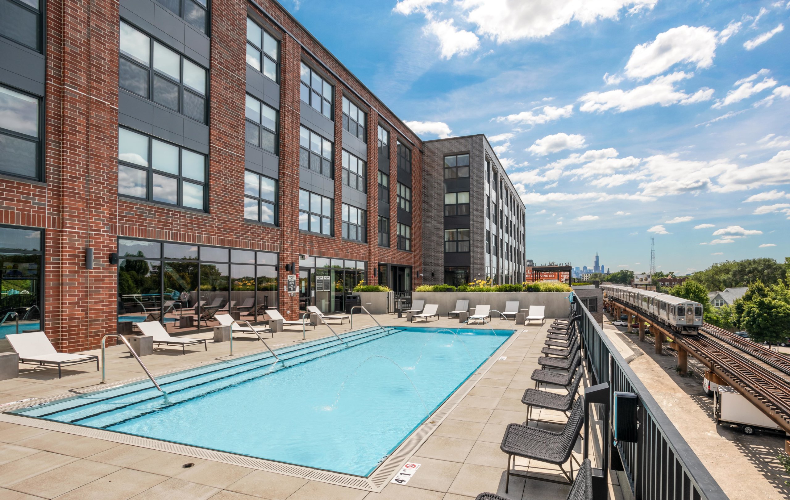 Logan Square Apartments pool deck with lounge chairs and benches