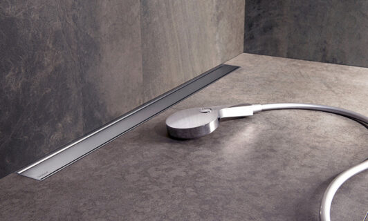 Modulo TAF Wall shower drain on the floor next to a shower head