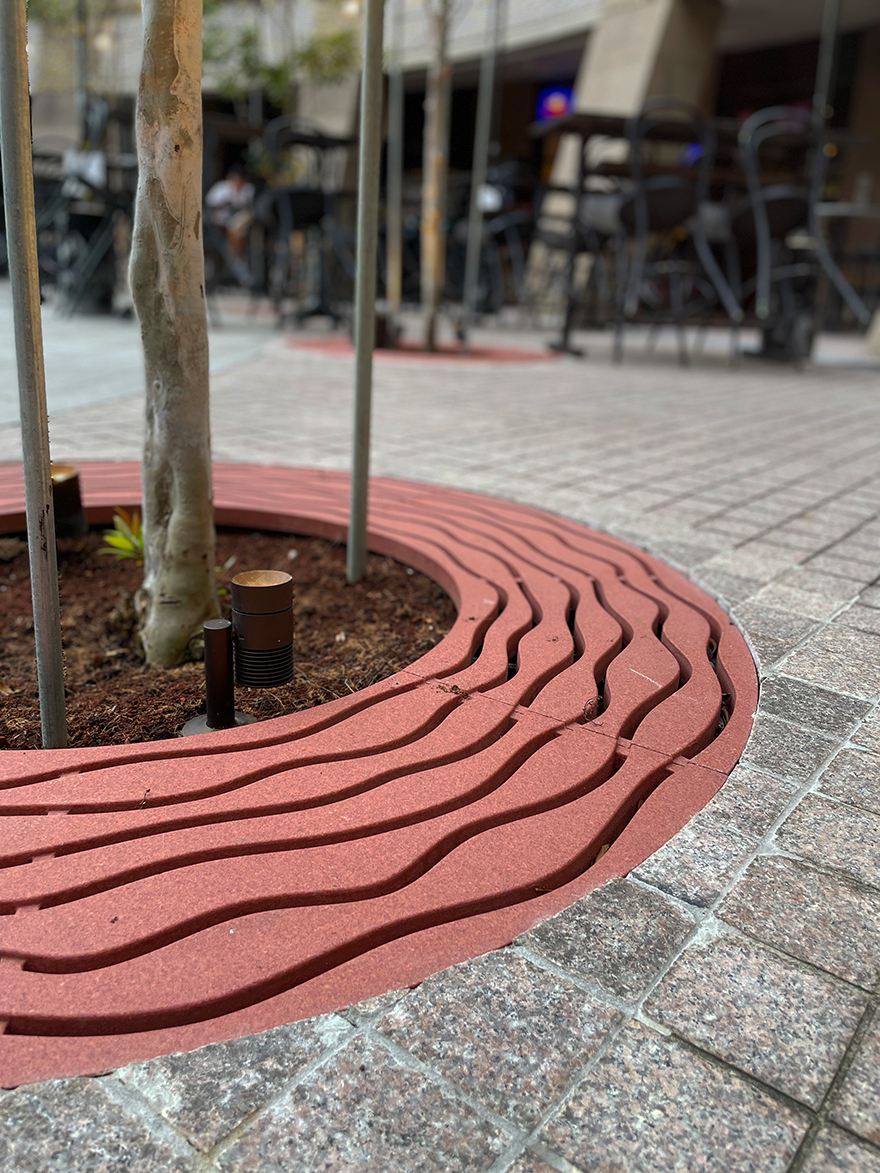 custom red stone tree grate around a tree at the Esplanade